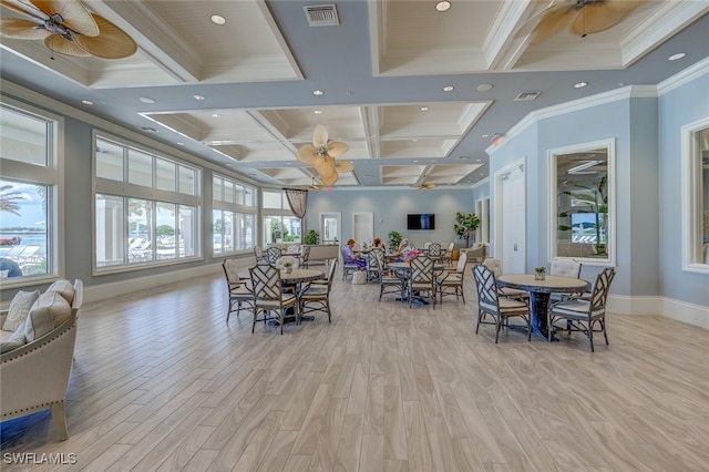 dining room featuring light hardwood / wood-style floors, a healthy amount of sunlight, crown molding, and coffered ceiling