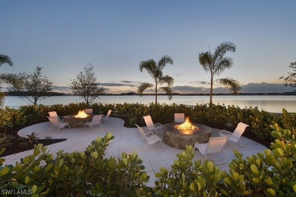 patio terrace at dusk featuring a fire pit and a water view