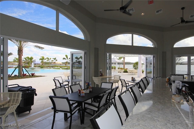 dining area featuring ceiling fan, plenty of natural light, and a water view