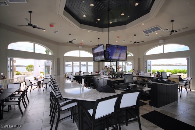 tiled dining area with a high ceiling, a tray ceiling, ornamental molding, and plenty of natural light