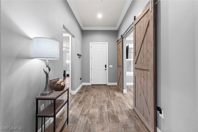 doorway to outside featuring wood-type flooring, a barn door, and crown molding