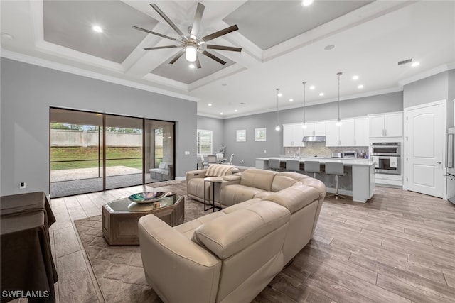 living room with ceiling fan, ornamental molding, light wood-type flooring, and coffered ceiling