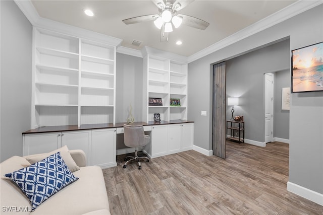 office featuring built in desk, ceiling fan, light hardwood / wood-style floors, and ornamental molding