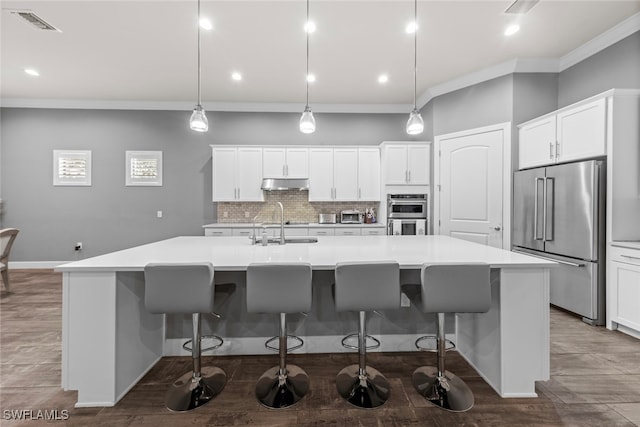 kitchen featuring a spacious island, a kitchen bar, stainless steel appliances, and hanging light fixtures