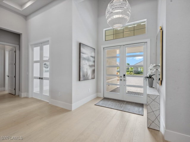 entrance foyer with light hardwood / wood-style floors, french doors, and a towering ceiling