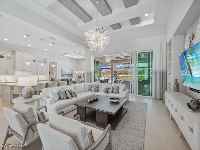 living room with a chandelier, a tray ceiling, and light wood-type flooring