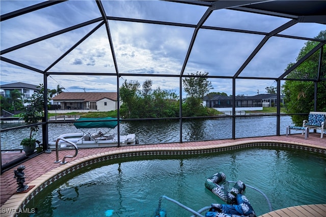 view of swimming pool with a patio, a water view, and a lanai