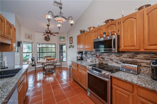 kitchen with tile patterned floors, light stone countertops, stainless steel appliances, and tasteful backsplash