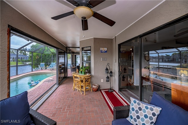 sunroom featuring a water view and ceiling fan