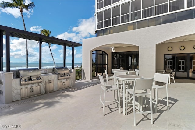 view of patio / terrace with a water view, a grill, and an outdoor kitchen