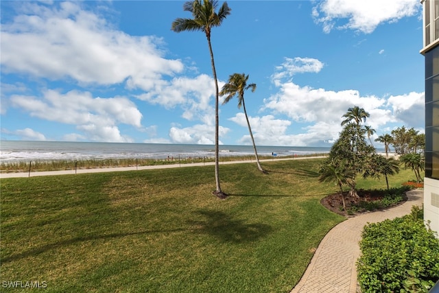 surrounding community featuring a water view, a lawn, and a view of the beach