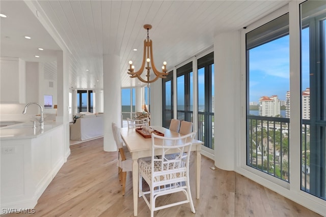 dining area featuring expansive windows, light hardwood / wood-style flooring, wooden ceiling, and an inviting chandelier