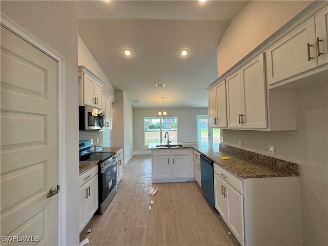 kitchen with kitchen peninsula, sink, stainless steel appliances, and vaulted ceiling