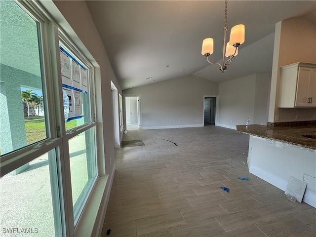 interior space featuring wood-type flooring, an inviting chandelier, and lofted ceiling