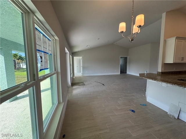2112 NW 22nd Ave, Cape Coral, FL 33993 - unfurnished living room with lofted ceiling, healthy amount of natural light, wood finished floors, a chandelier, and baseboards