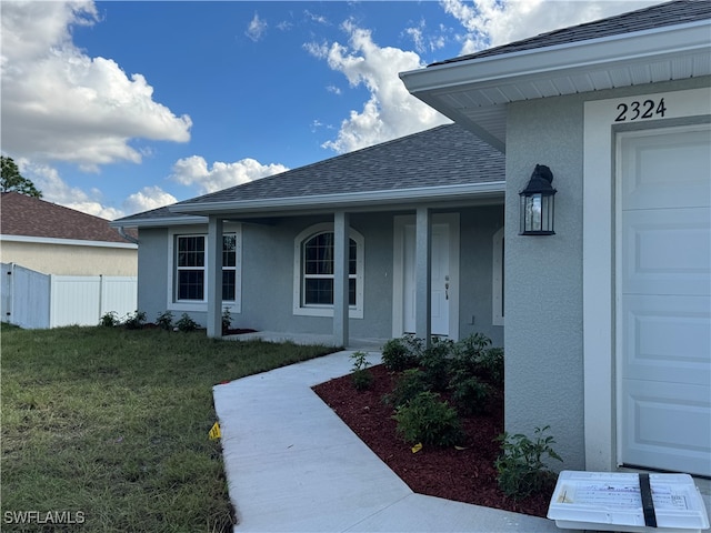 view of exterior entry with a yard and a garage