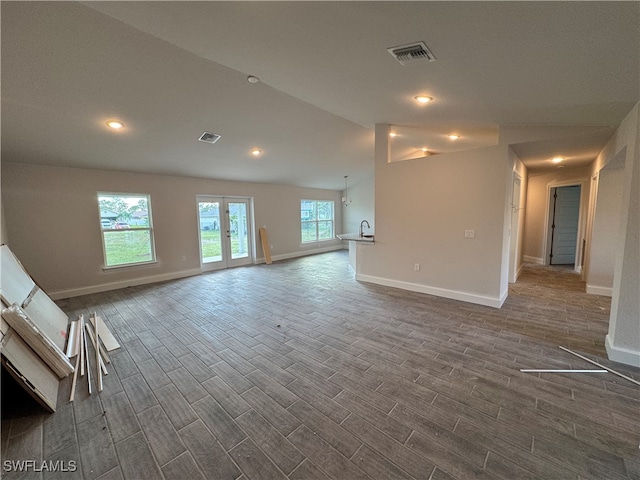 unfurnished living room featuring lofted ceiling and dark wood-type flooring