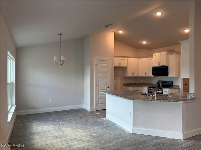 kitchen with kitchen peninsula, dark hardwood / wood-style flooring, vaulted ceiling, dark stone countertops, and white cabinets