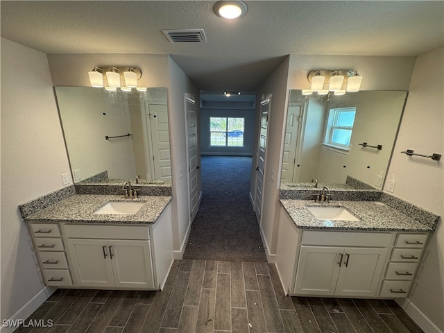 bathroom featuring hardwood / wood-style flooring, vanity, a healthy amount of sunlight, and a textured ceiling