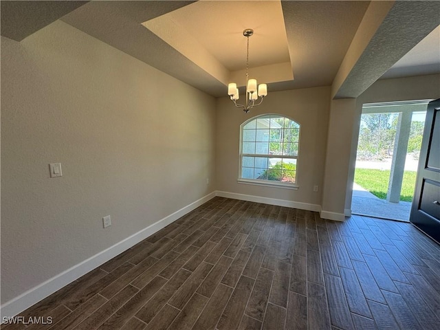 2324 Jacaranda Pkwy W, Cape Coral, FL 33993 - unfurnished dining area with dark wood-style flooring, a textured wall, an inviting chandelier, a raised ceiling, and baseboards