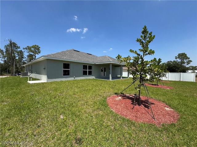 2324 Jacaranda Pkwy W, Cape Coral, FL 33993 - back of house with a lawn, fence, cooling unit, and stucco siding