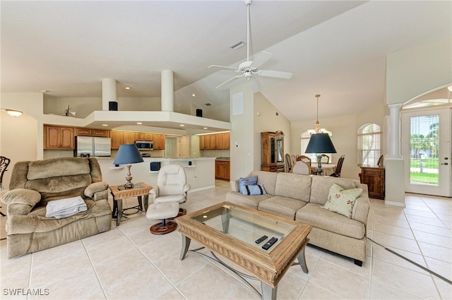 living room with decorative columns, high vaulted ceiling, light tile patterned floors, and ceiling fan