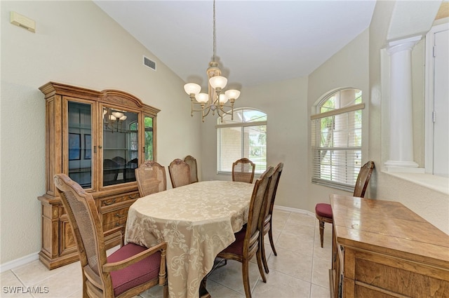 tiled dining space featuring decorative columns, lofted ceiling, and a chandelier