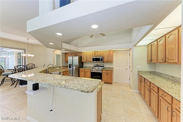 kitchen with hanging light fixtures, light tile patterned floors, a textured ceiling, sink, and stainless steel appliances