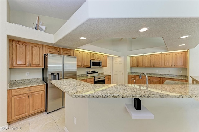 kitchen featuring light stone countertops, sink, light tile patterned flooring, appliances with stainless steel finishes, and a textured ceiling