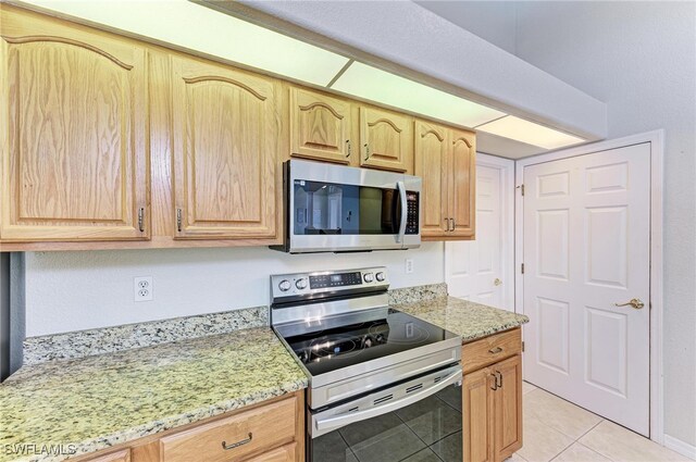 kitchen featuring stainless steel appliances, light stone counters, and light tile patterned floors