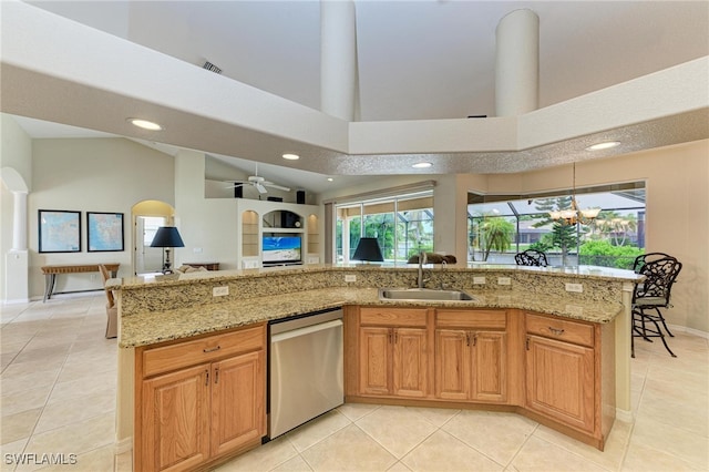 kitchen with stainless steel dishwasher, sink, light tile patterned flooring, and light stone counters