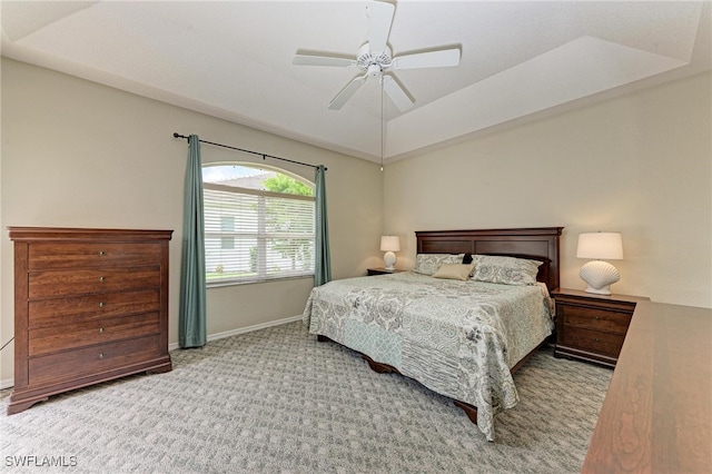 carpeted bedroom with ceiling fan and a tray ceiling