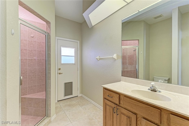 bathroom with toilet, vanity, tile patterned floors, and a shower with door