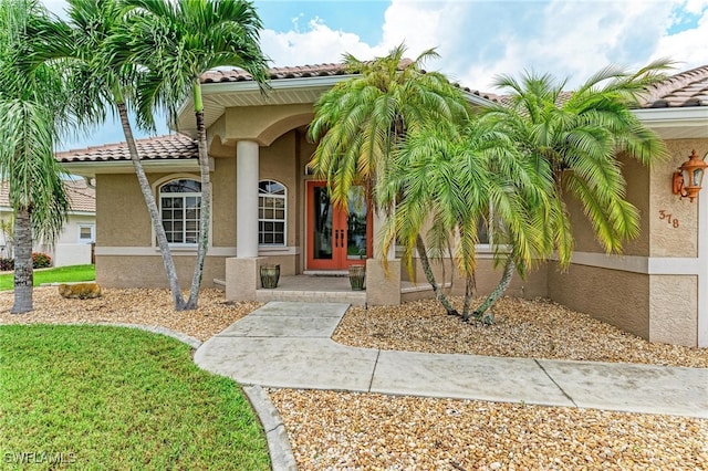 view of exterior entry with french doors and a lawn