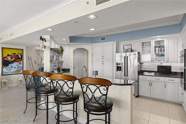 kitchen with light tile patterned flooring, white cabinetry, tasteful backsplash, and high quality fridge