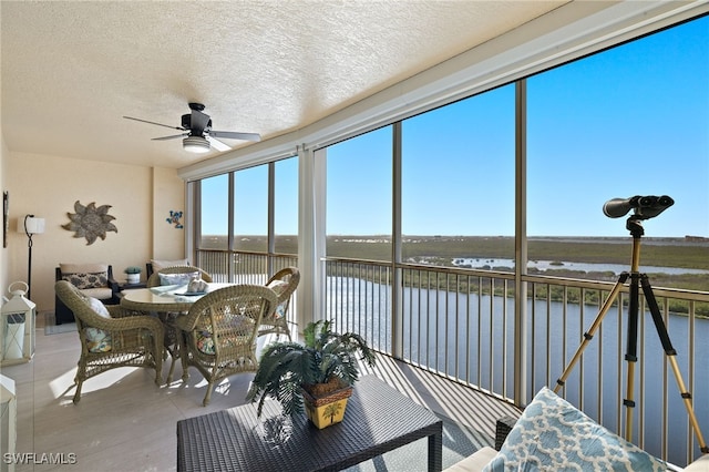 sunroom featuring a water view and ceiling fan