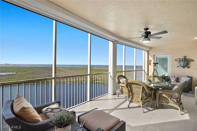 sunroom featuring a water view and ceiling fan