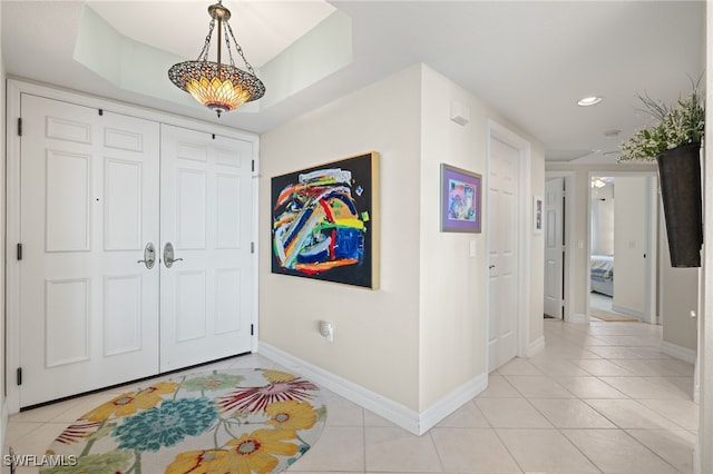 entryway featuring light tile patterned flooring and a raised ceiling