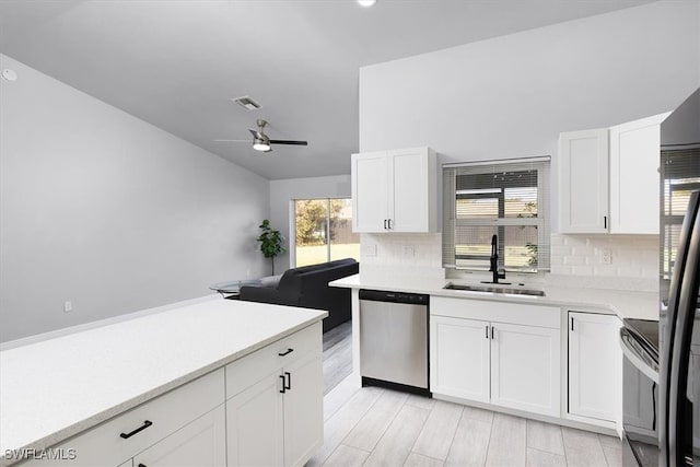 kitchen with stainless steel appliances, decorative backsplash, sink, and white cabinets