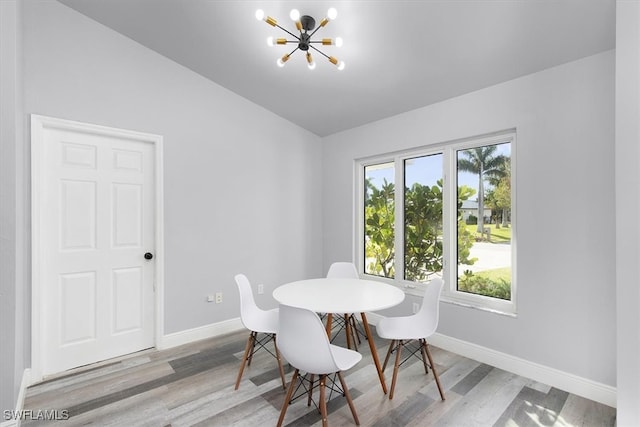 dining space featuring light hardwood / wood-style floors, lofted ceiling, and a chandelier