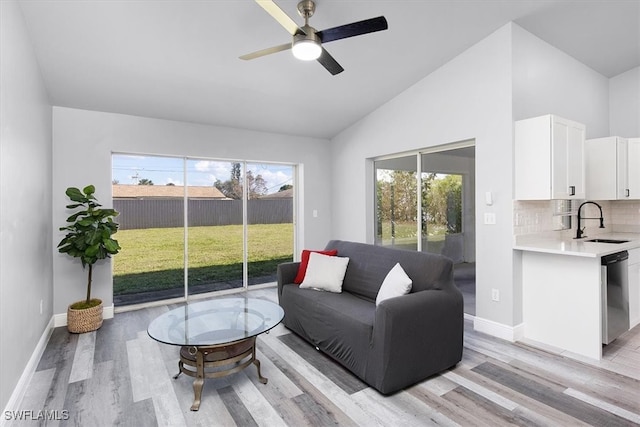 living room featuring light hardwood / wood-style floors, high vaulted ceiling, sink, and ceiling fan