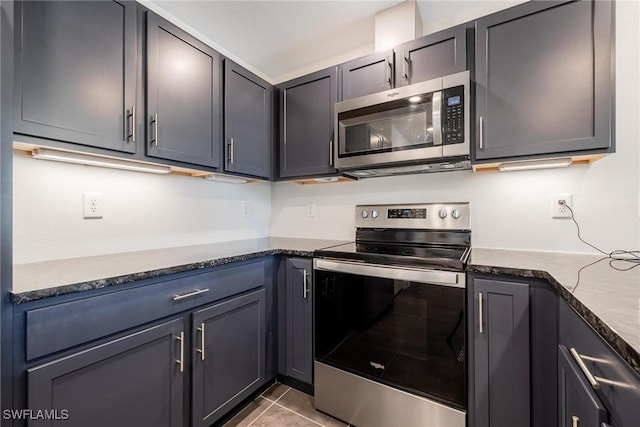 15050 Caspian Tern Ct Unit 102, North Fort Myers, FL 33917 - kitchen featuring stainless steel appliances, light tile patterned floors, and dark stone counters