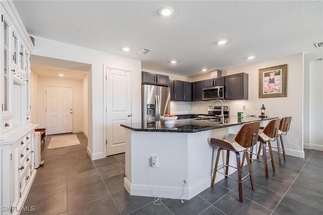 15050 Caspian Tern Ct Unit 102, North Fort Myers, FL 33917 - kitchen with a sink, a peninsula, stainless steel appliances, dark stone countertops, and baseboards