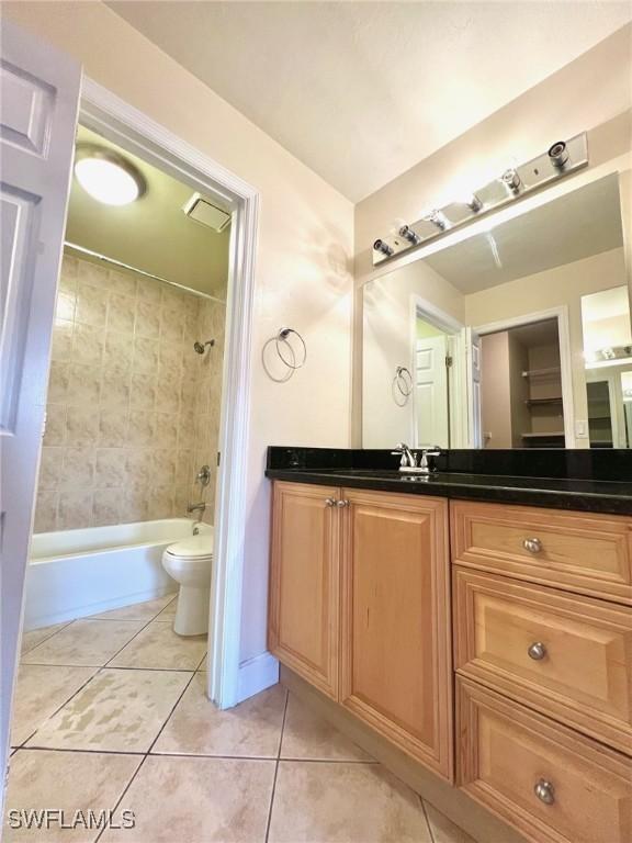 full bathroom featuring tile patterned flooring, vanity, toilet, and tiled shower / bath combo