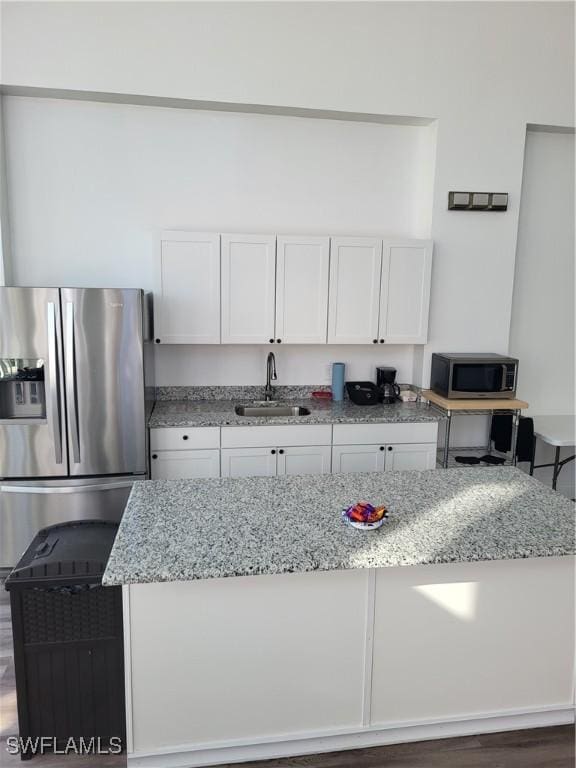 kitchen featuring sink, light stone counters, appliances with stainless steel finishes, dark hardwood / wood-style flooring, and white cabinetry