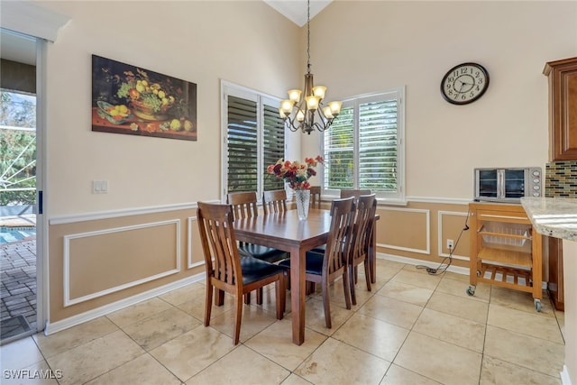 tiled dining area with high vaulted ceiling and a chandelier