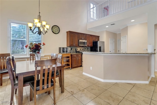 dining space with an inviting chandelier, light tile patterned floors, crown molding, and a towering ceiling