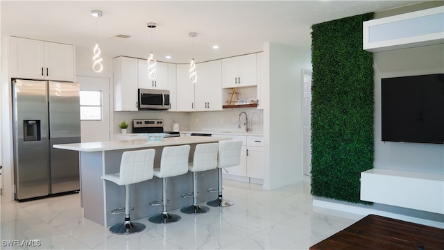 kitchen with sink, a center island, hanging light fixtures, white cabinetry, and stainless steel appliances