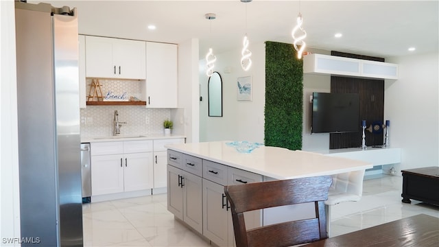 kitchen with backsplash, appliances with stainless steel finishes, white cabinetry, decorative light fixtures, and sink