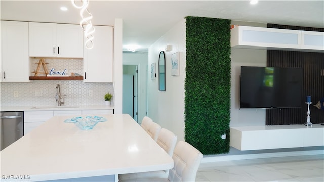 kitchen with decorative backsplash, dishwasher, sink, a kitchen bar, and white cabinets